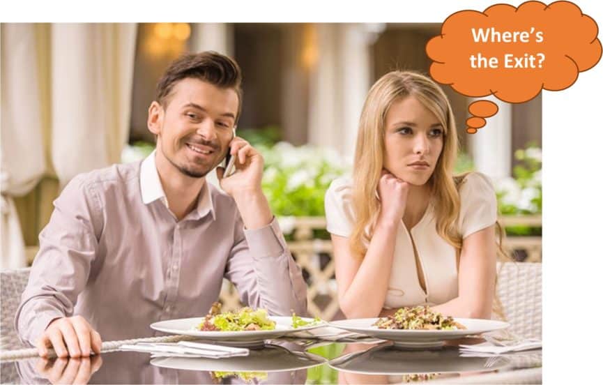 An Image of a man on a cell phone call having a meal with a woman